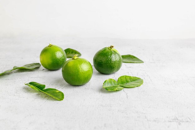 Folhas de limão verde fresco e limão na mesa de madeira branca