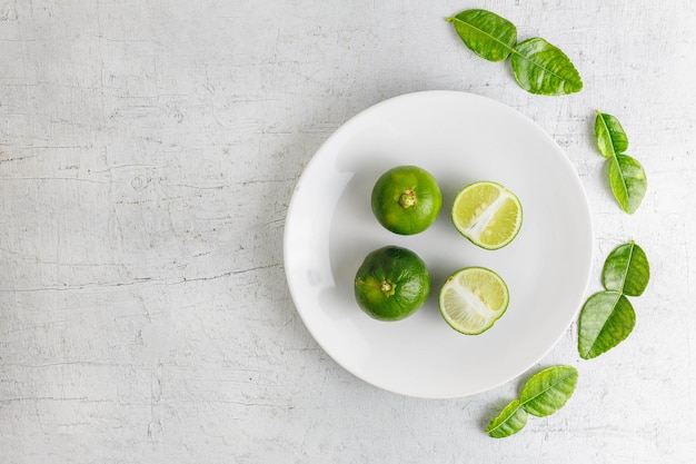 Folhas de limão verde fresco e limão na mesa de madeira branca