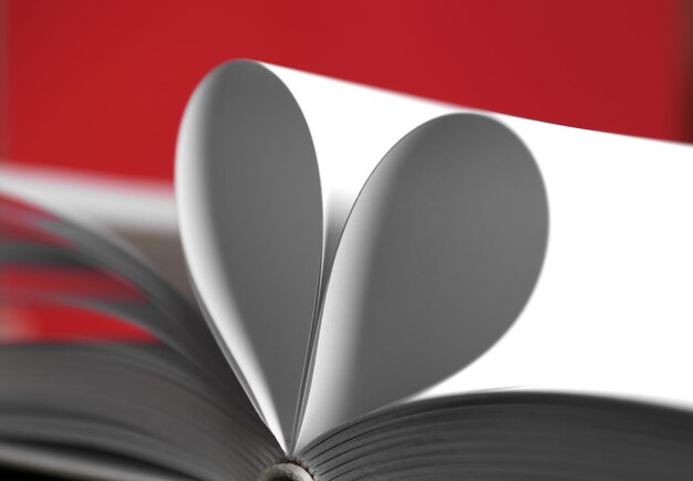 Folhas de livro curvadas em forma de coração em fundo vermelho desfocado