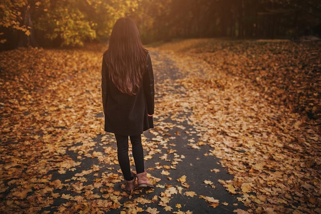 Folhas de outono caindo na mulher jovem feliz na floresta