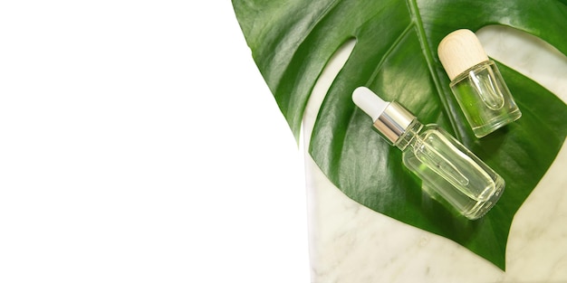 Folhas de palmeira tropicais sobre fundo de mármore Óleo essencial em garrafa de vidro Conceito de spa para cosméticos naturais e cuidados com a pele