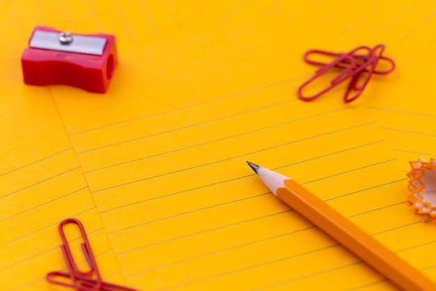 Folhas de papel laranja, lápis, artigos de papelaria e espaço vazio para o seu texto de conceito.