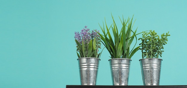 Folhas falsas de alfazema e verde ou planta artificial em vaso na mesa com fundo azul e verde ou hortelã.