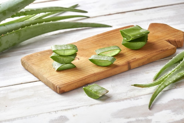 Folhas frescas de aloe vera e fatias com água cai sobre fundo de madeira. conceito de medicina natural