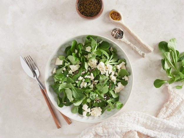 Folhas frescas de salada de milho verde ou alface de cordeiro com queijo feta servido em molho de soja e sementes de gergelim Vista superior