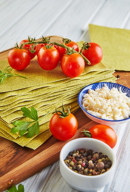 Folhas para fazer lasanha com espinafre e ingredientes, tomate cereja, queijo