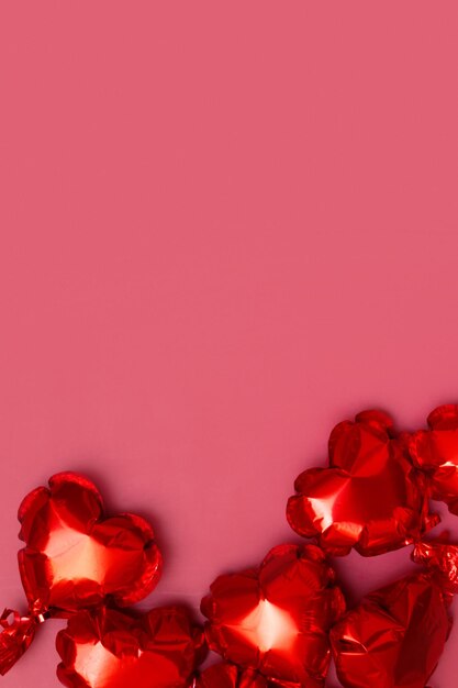 Folienballons in Form eines Herzens auf einer Draufsicht des roten Hintergrundes. Platz kopieren. Festlicher vertikaler Hintergrund zum Valentinstag