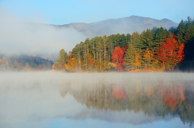 Follaje de otoño y lago de niebla por la mañana