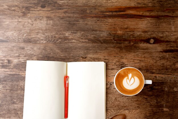 Folleto en blanco en la mesa de madera con una taza de café