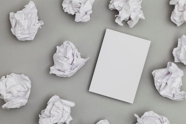 Folleto de postal de tarjeta blanca en blanco sobre un fondo gris con papel arrugado