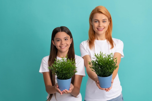 Fomentar para adoptar. Familia adoptiva. La hija adoptiva y la madre sostienen plantas de interior. Adopción de niños. Infancia feliz.