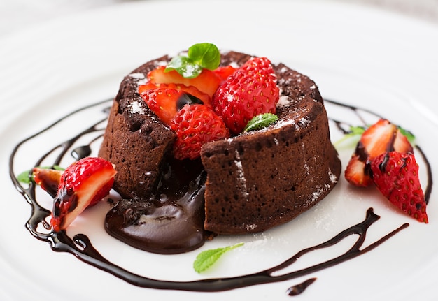 Fondant de chocolate (cupcake) con fresas y azúcar en polvo