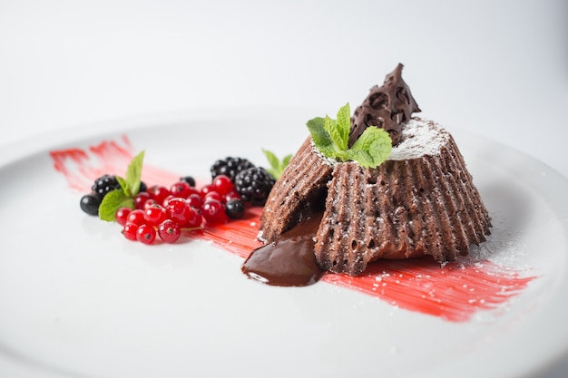 Fondant de chocolate com frutas e hortelã no prato branco.