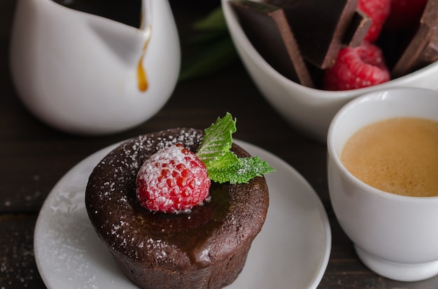 Fondant de chocolate com xícara de café raspberryand. bolo de chocolate derretido com fundo de açúcar de confeiteiro.