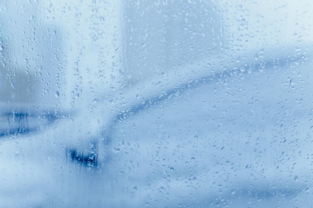 Fondo abstracto de invierno. Una calle vista a través de un cristal con gotas de condensación