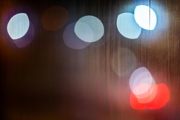 Un fondo abstracto luces de la calle de noche bokeh a través de un primer plano de vidrio húmedo con enfoque selectivo