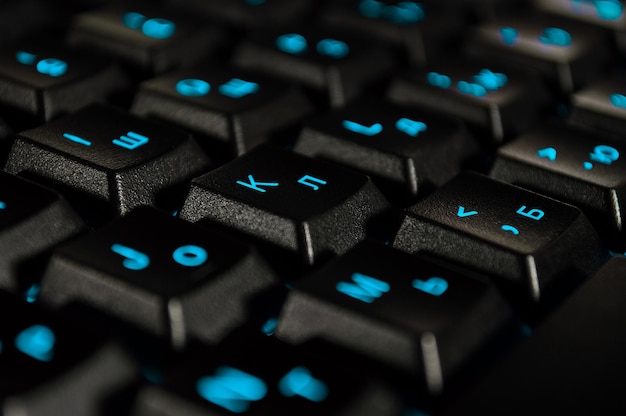 Fondo abstracto de teclado de computadora negro con luz de fondo azul La foto de primer plano con bokeh se puede usar como fondo de pantalla