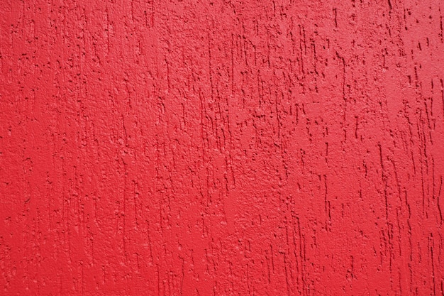 Fondo abstracto y textura de una pared enlucida en rojo brillante con textura de escarabajo de corteza