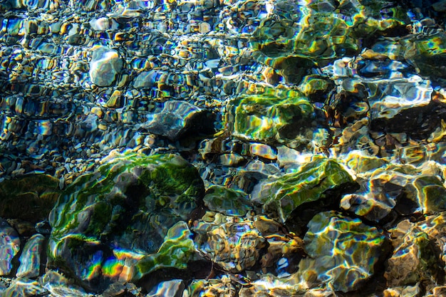 Fondo abstracto y textura de piedras de colores y guijarros bajo el agua en el río.