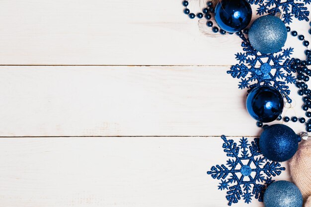 Fondo de adornos de adornos navideños. Bolas de vidrio, estrellas azules y abalorios en la mesa blanca de madera