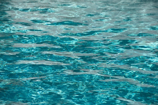 Fondo de agua azul en la piscina con reflejo del sol onda de agua ondulada en el agua clara de la piscina...