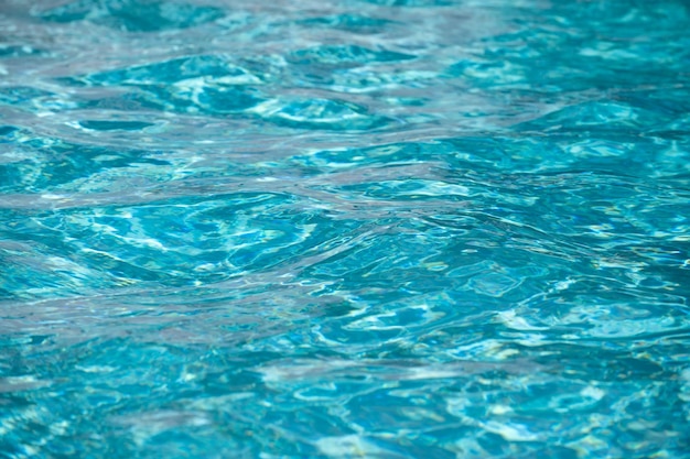 Fondo de agua azul en la piscina con reflejo del sol onda de agua ondulada en el agua clara de la piscina