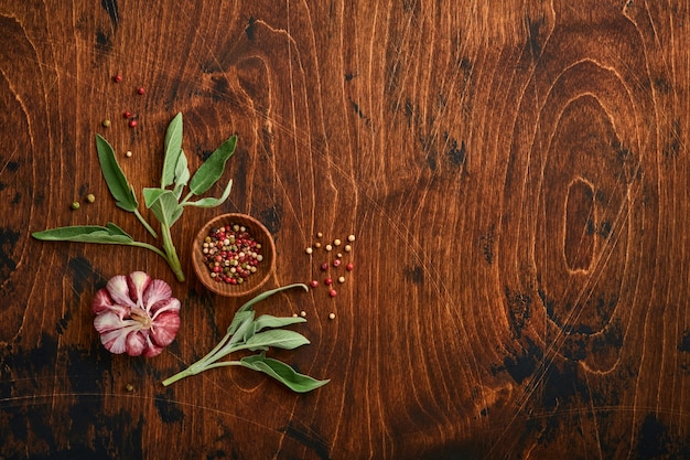 Fondo de alimentos. Especias, hierbas, hoja de salvia, pimiento multicolor y utensilios de cocina. Vista superior. Espacio para tu texto. Estilo rústico.