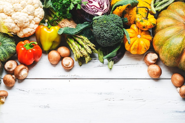 Fondo de alimentos con ingredientes de cocina vegetariana Verduras orgánicas calabaza champiñones espárragos pimentón coliflor en espacio de copia de mesa de madera blanca