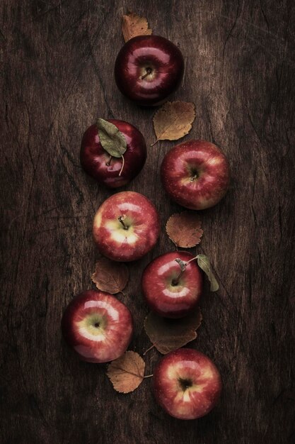 Fondo de alimentos de otoño Manzanas maduras con hojas caídas en la mesa de madera rústica Vista superior Espacio de copia