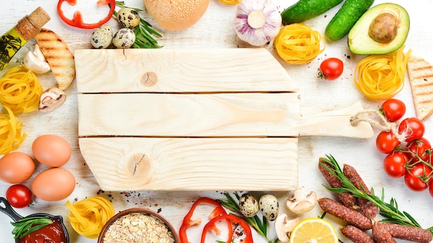 Fondo de alimentos Pasta seca tomates especias y verduras sobre un fondo blanco de madera Vista superior