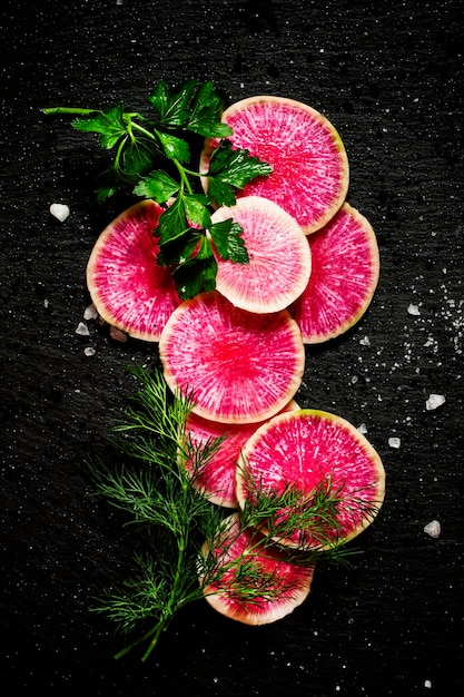 Fondo de alimentos rebanadas redondas de sandía rosa rábano eneldo perejil sal fondo de piedra negra vista superior