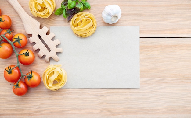 Fondo de alimentos para sabrosos platos italianos con papel marrón en blanco y cuchara de pasta vintage sobre fondo de madera.