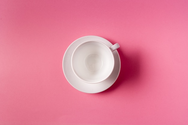 Fondo de alimentos con taza blanca vacía, sobre fondo de color rosa pastel, endecha plana.