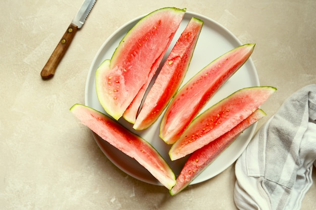 Fondo de alimentos de verano. Rebanadas de sandía madura en un plato, sobre un fondo cálido