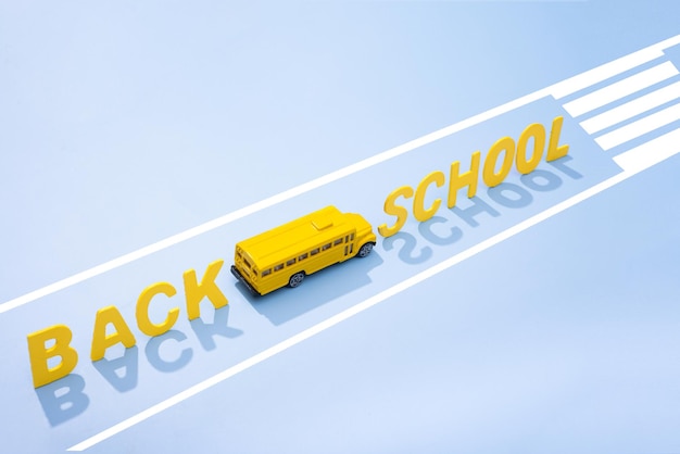 En un fondo amarillo, un autobús escolar amarillo con marcas viales de regreso a la foto del concepto escolar