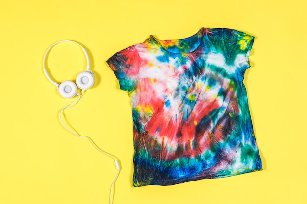 Fondo amarillo con camiseta tie dye y auriculares Lay Flat