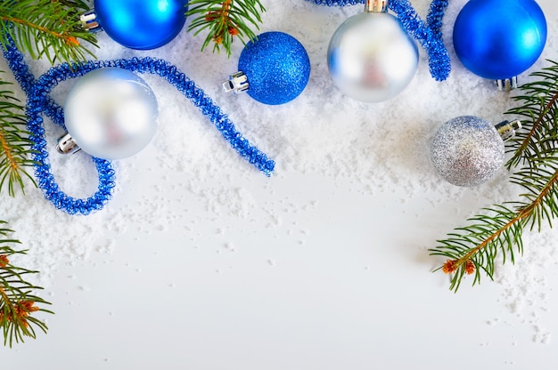 Fondo de año nuevo con bolas de Navidad azules y plateadas en la nieve