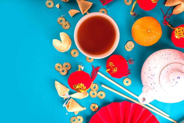 Fondo de año nuevo chino. Flatlay rojo y amarillo dorado con decoración tradicional china de año nuevo, sobres con deseos, monedas de oro, ventiladores, linternas chinas, naranjas y té