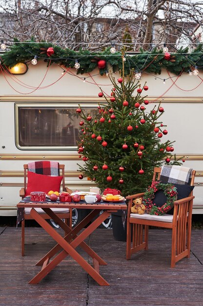 Fondo de árbol de Navidad. Furgoneta remolque móvil, casa móvil, terraza. Celebración de Año Nuevo. Vacaciones de invierno. Mañana de Navidad. Autocaravana en campamento, autocaravana.