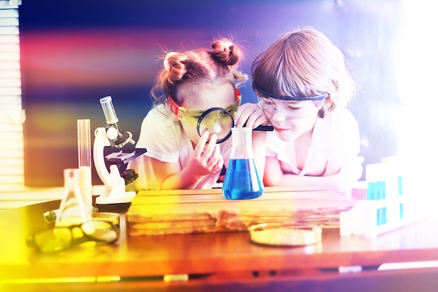 Fondo con aspectos destacados de los hijos de los científicos Un niño y una niña están experimentando en el laboratorio