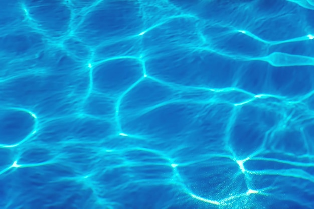 Fondo azul del agua de la ondulación, reflejo del sol del agua de la piscina