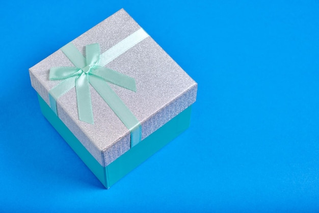 El fondo azul de la caja de regalo está atado con una cinta turquesa con lazo