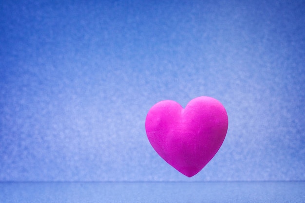 Fondo azul liso con pequeño corazón rojo violeta