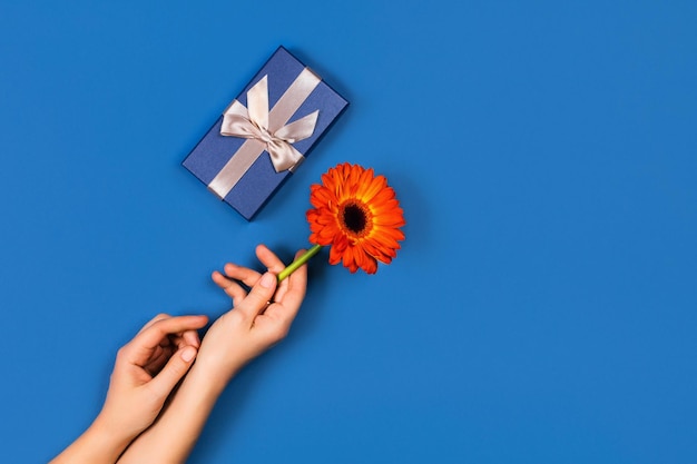 Fondo azul con manos y regalo para el Día de San Valentín