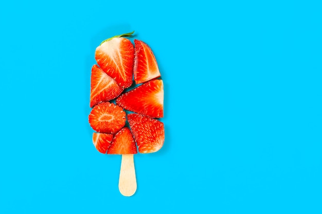 Un fondo azul con una paleta con fresas.