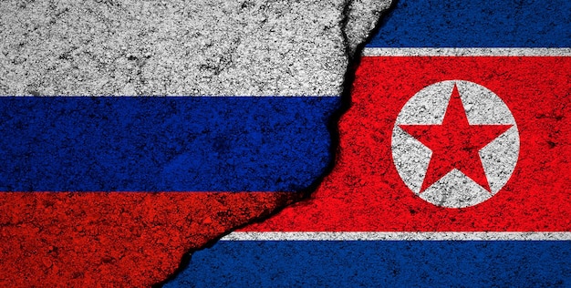 Fondo de banderas de rusia y corea del norte muro agrietado conflicto militar y foto de concepto de guerra