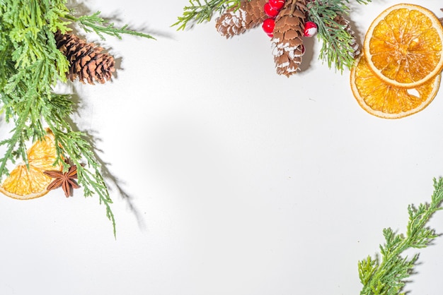 Fondo blanco azul claro de invierno de Navidad, con ramas de abeto, conos de pino, naranja seca, especias, ingredientes para cócteles de invierno, decoraciones, espacio de copia de vista superior plana