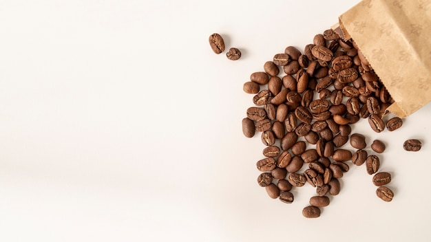 Fondo blanco con granos de café en bolsa de papel