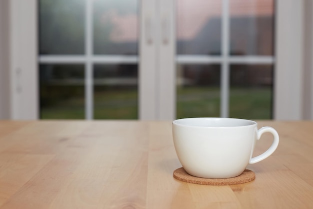 Fondo borroso de cocina y taza de té blanca