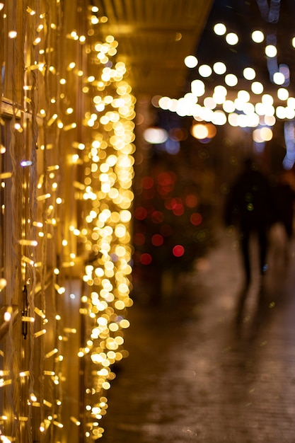 Foto fondo borroso dorado con luces de guirnaldas de navidad en la noche en la calle de noche